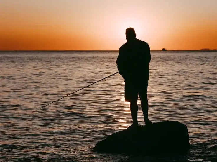 Homme pêchant en mer au coucher du soleil, illustrant l'article sur quelle canne choisir pour pêcher en mer du bord ?
